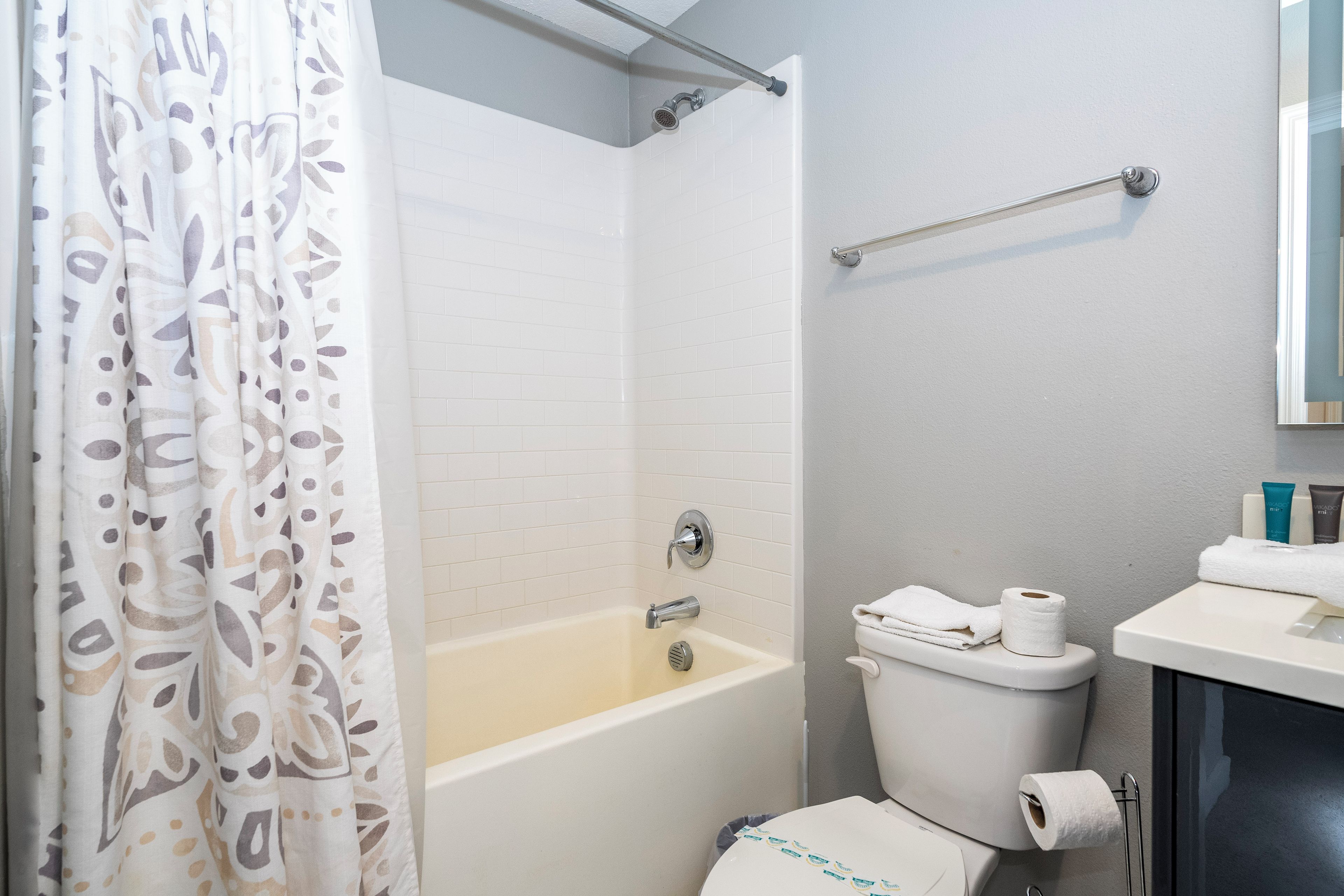 A bathroom with a bathtub, toilet, and shower curtain.