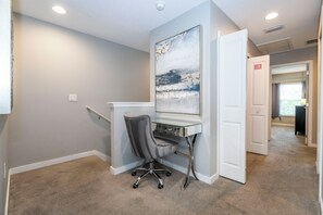 A room with a desk, chair, and a painting on the wall. - 4BR Private Pool Near Disney & Supermarkets (Kissimmee)