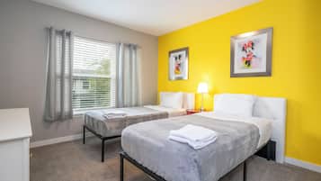 Ein Hotelzimmer mit zwei Betten, einem Vorhangfenster und zwei gerahmten Bildern an der Wand.