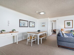 Ein modernes Wohnzimmer mit einer Couch, einem Esstisch mit Stühlen und einer Küchenzeile mit Arbeitsplatte und Schränken.