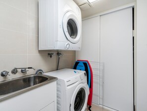 Ein kleiner Waschbereich mit einer Frontlademaschine, einem Trockner und einem Schlauch.