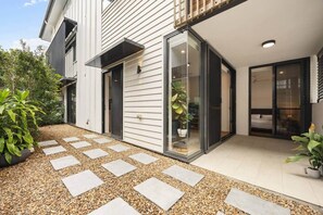 Ein modernes Haus mit Terrasse, einem Blumentopf und einem Weg.