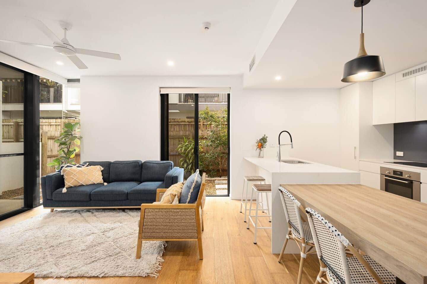 A modern living room with a dark blue sofa, a wooden coffee table, and a white rug.