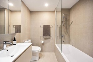 Un bagno moderno con doccia a vetro, lavandino bianco e water.