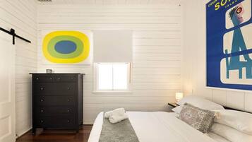 A bedroom with a bed, a dresser, a window, and a poster on the wall.