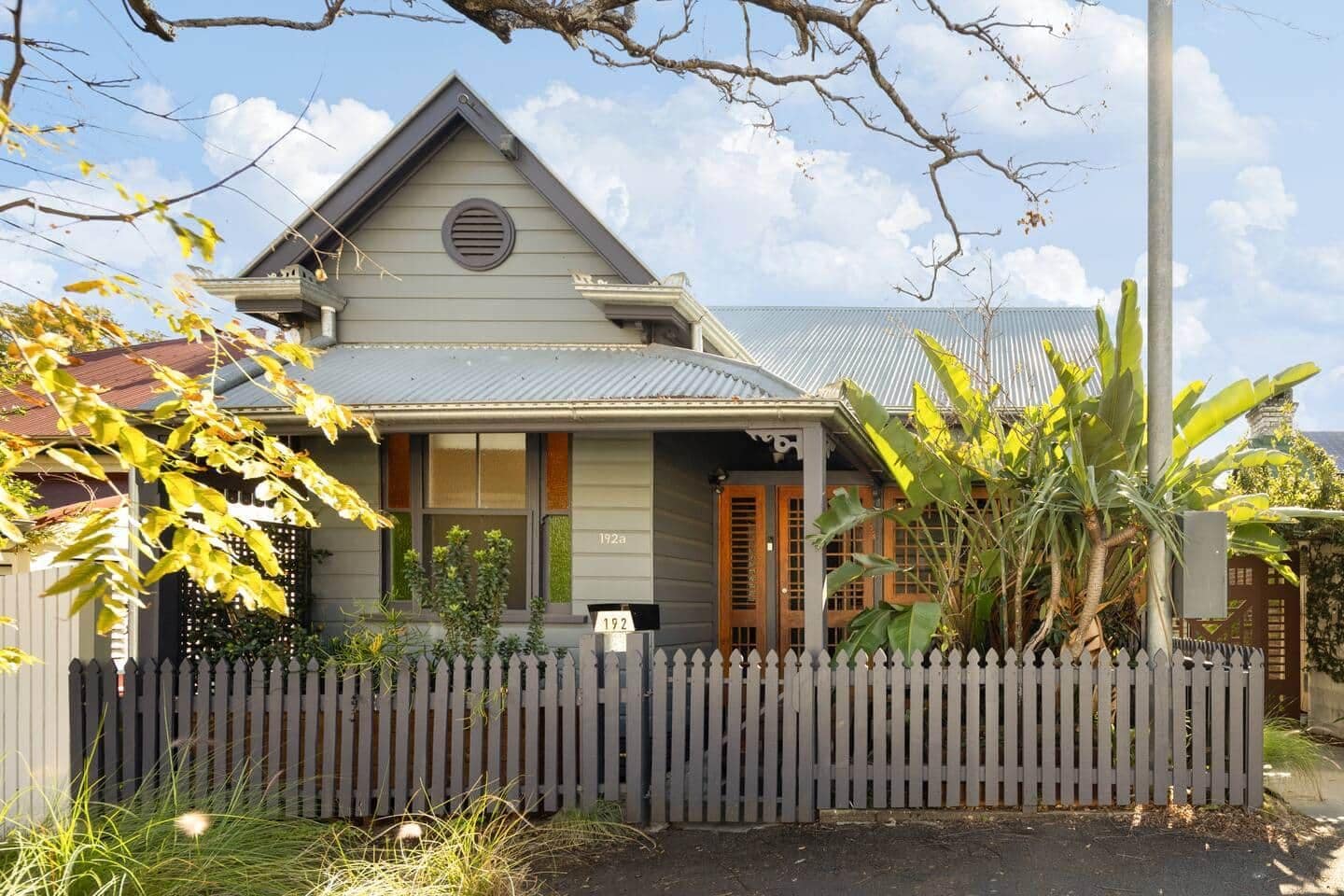 A residential house with a gabled roof, a front porch, and a picket fence.