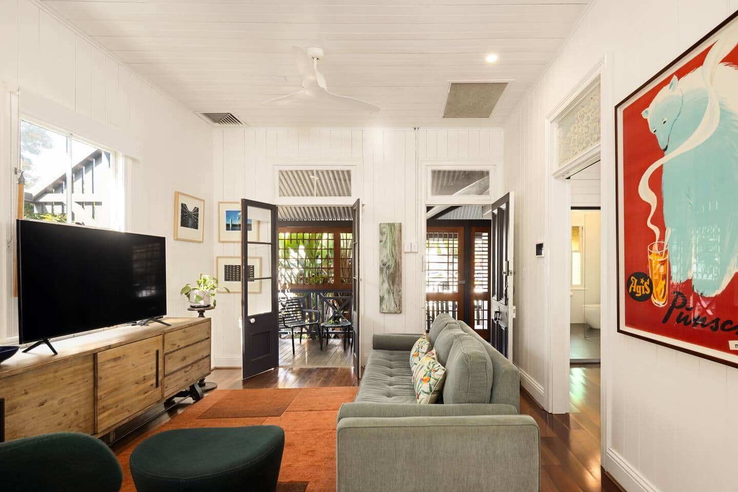 A living room with a television, sofa, and ottoman. There is a dining area with chairs and a table.