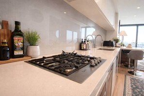 Een moderne keuken met een gasfornuis, een spoelbak en een bar met krukken.