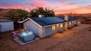 Ein modernes Haus mit Natursteinfassade, einem Whirlpool und einem Solardach.