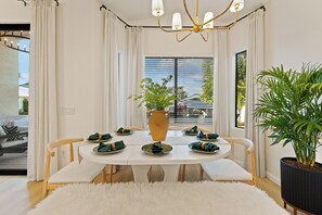 A dining area with a round table set for four, white curtains, a large window with blinds, and a potted plant. - Private Waterfront resort. FREE heated pool, Jacuzzi. Boat, Sauna. Ocotillo (Chandler)