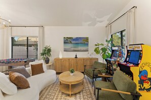 A living room with a foosball table, a sofa, a coffee table, and a gaming console. - Private Waterfront resort. FREE heated pool, Jacuzzi. Boat, Sauna. Ocotillo (Chandler)