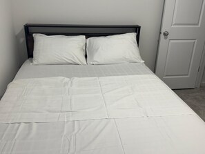 A single bed with a dark headboard and white bedding. - Cozy 1 Bedroom Legal Basement Suite, Shops, transit close by. 15min. to Airport, (Edmonton)