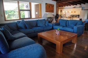 A living room with a sectional sofa, a coffee table, and a kitchen in the background. - Casa Los Mangos - Private Dock on the Lake (Santa María Del Oro)