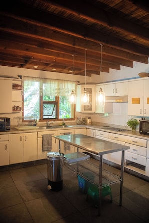 A kitchen with a central island, stainless steel appliances, and a window with a view of greenery. - Casa Los Mangos - Private Dock on the Lake (Santa María Del Oro)