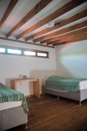 A room with two beds, a small table, and a window. - Casa Los Mangos - Private Dock on the Lake (Santa María Del Oro)