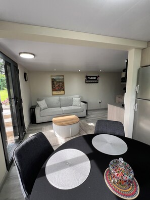 A modern living room with a sofa, a coffee table, and a dining table with placemats. - Perfect 1-bedroom apartment in beautiful Bajo Boquete getaway (Bajo Boquete)