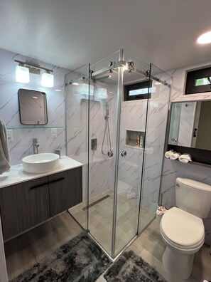 A modern bathroom with a glass-enclosed shower, a white sink, and a toilet. - Perfect 1-bedroom apartment in beautiful Bajo Boquete getaway (Bajo Boquete)