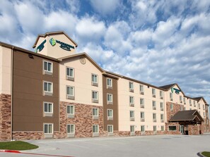 A multi-story hotel with a flat roof, large windows, and a prominent logo on the facade. - Room in Plano (Plano)