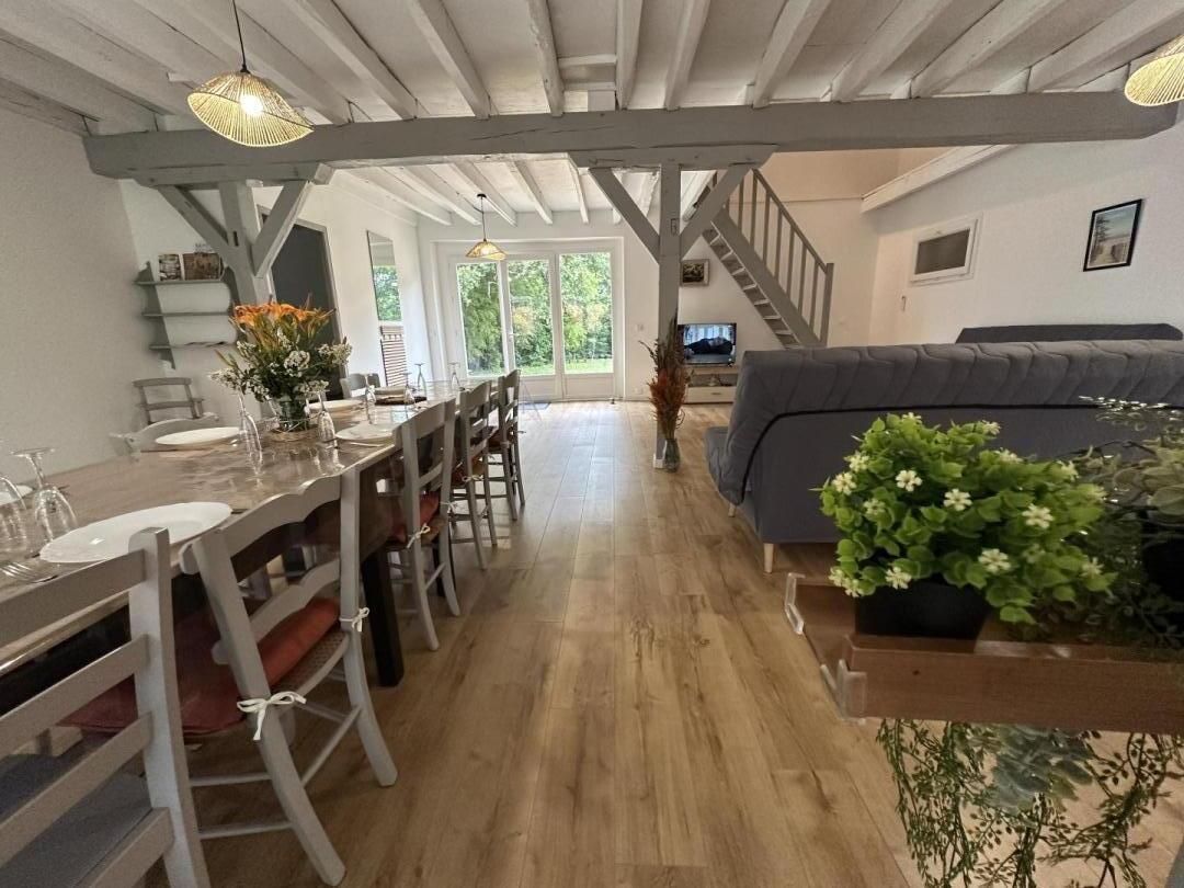 Un vaste espace de vie doté d’un plancher en bois, d’un canapé gris et d’une table à manger avec des chaises.