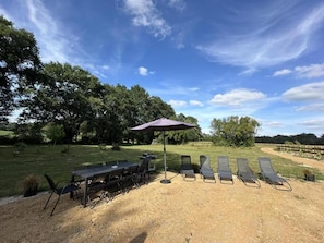 An outdoor seating area with a table and chairs, a sun umbrella, and lounge chairs. - The Landaise Barn - LAGLORIEUSE (LAGLORIEUSE)