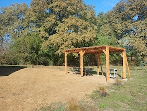 A wooden pergola structure in a grassy outdoor area with trees in the background. - The Landaise Barn - LAGLORIEUSE (LAGLORIEUSE)