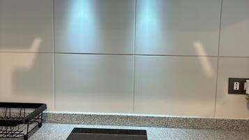 Una cocina con tope de inducción negro, azulejos blancos y campana extractora de acero inoxidable.