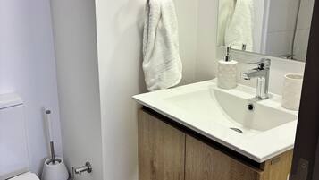 Un baño moderno con lavamanos blanco, mueble de madera y un espejo.