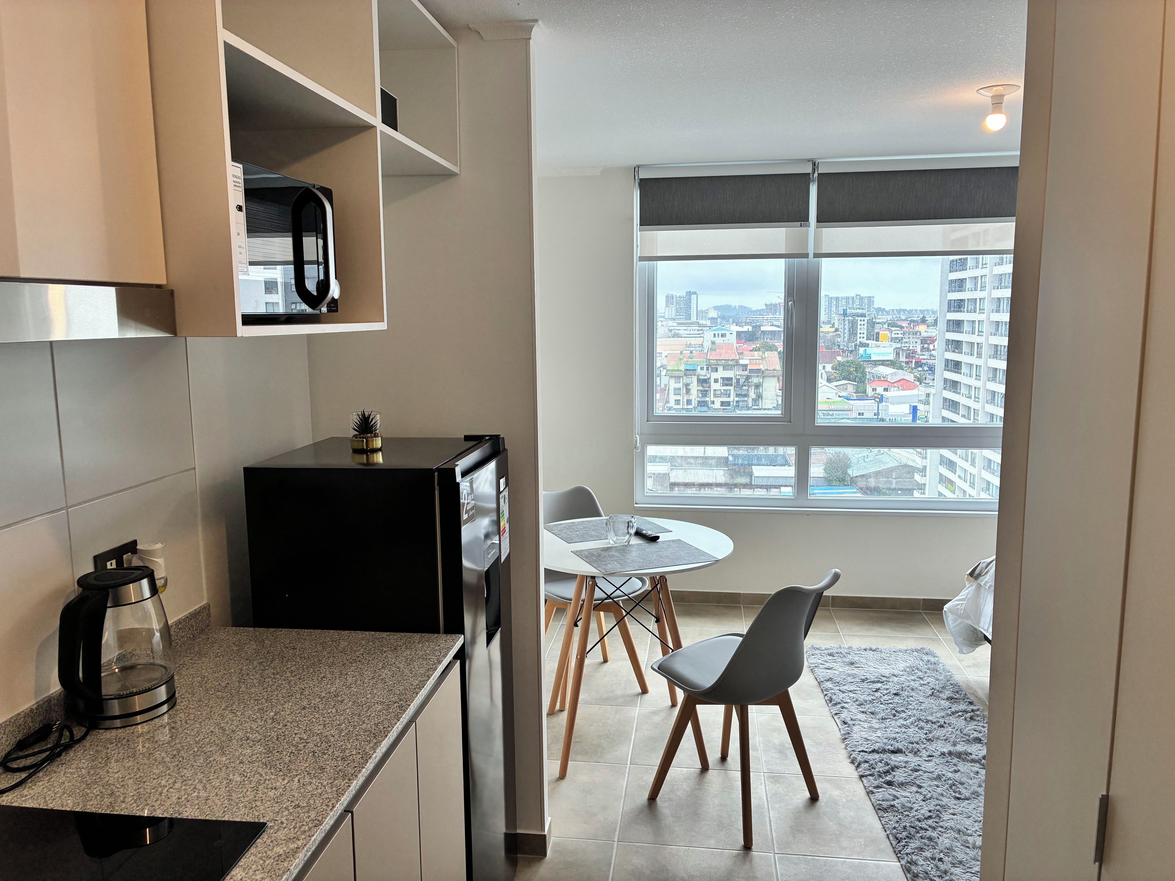 A modern kitchen with a built-in refrigerator, a coffee maker, and a dining area with a table and chairs.