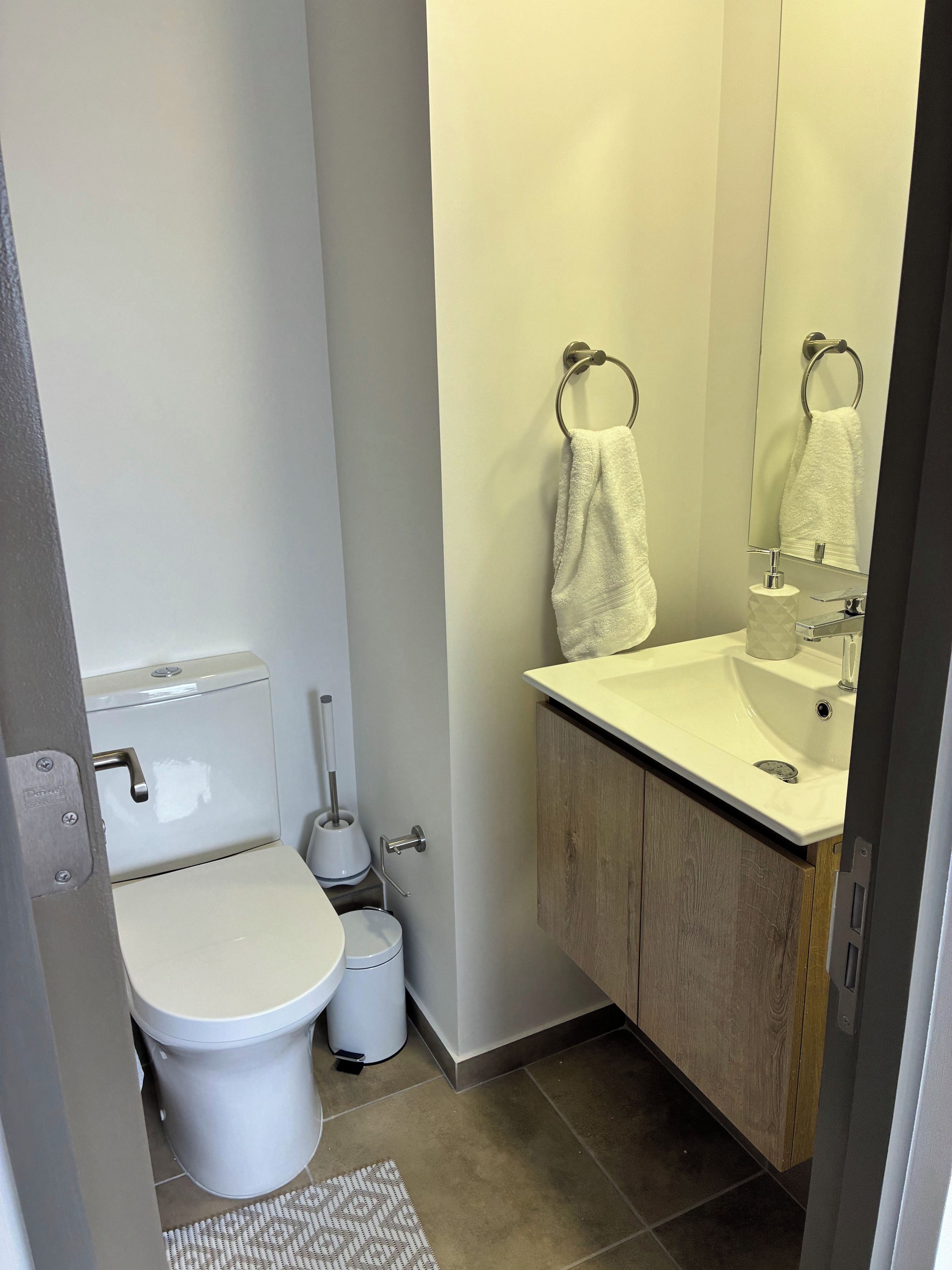 A modern bathroom with a toilet, bidet, sink, and mirror.