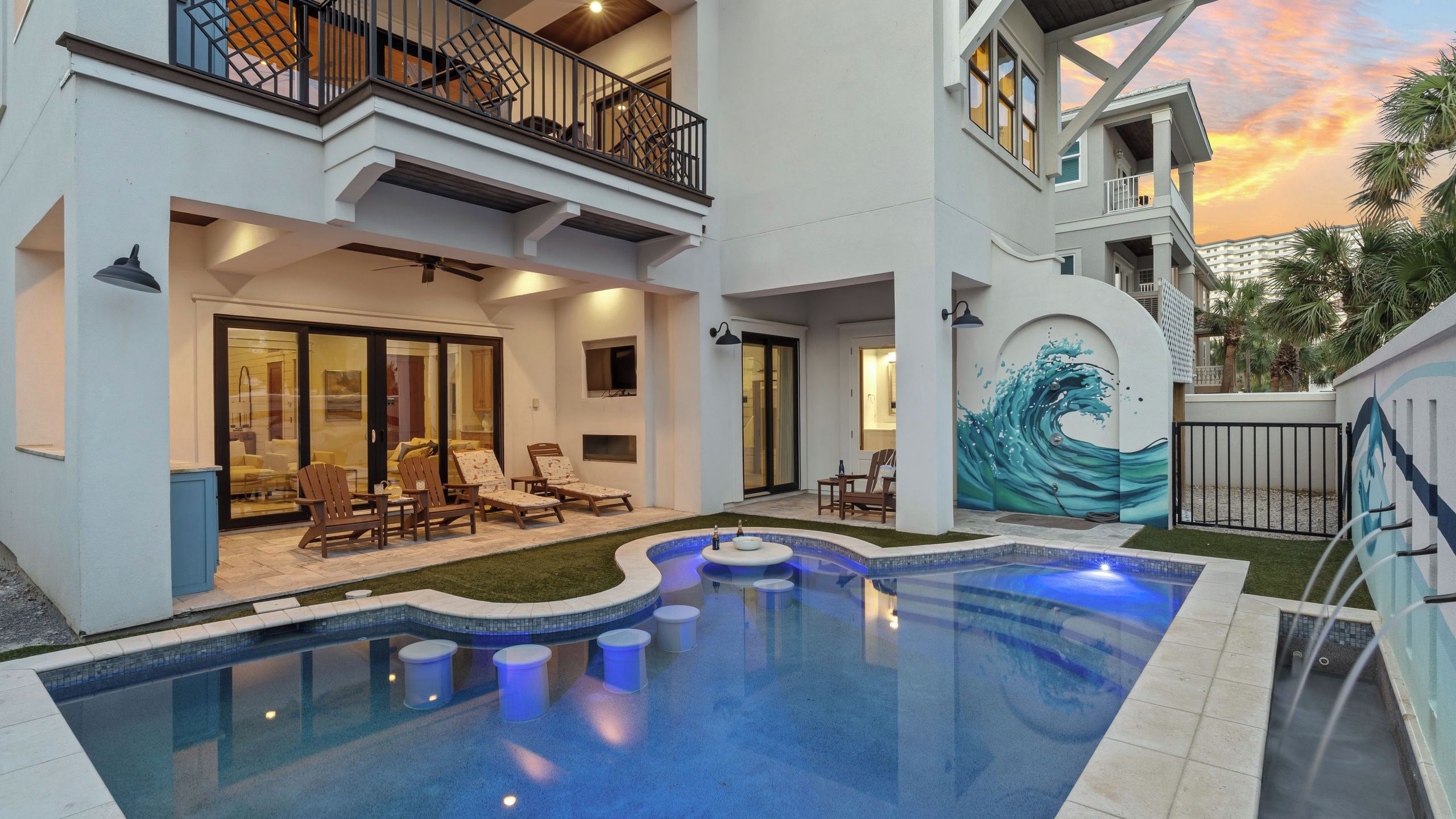 A modern two-story house with a swimming pool, outdoor seating, and a mural on the exterior wall.
