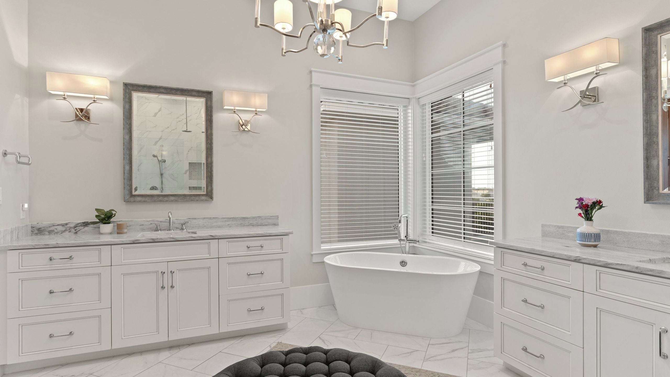 A modern bathroom with a freestanding bathtub, white cabinetry, and a large mirror.