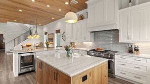 A modern kitchen with a central island, stainless steel appliances, and a wooden ceiling. - Sea E O by Avantstay Sleeps 24 Private Pool + Elevator Gulf Views + Steps to the Beach (Destin)