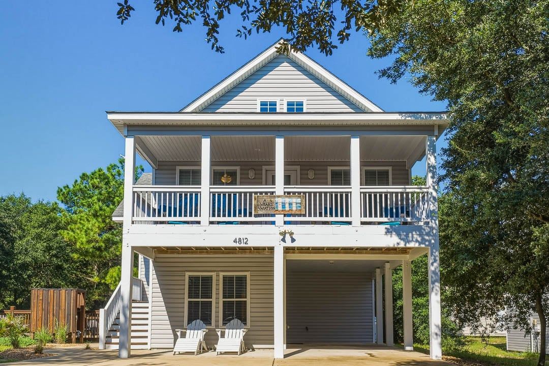 A two-story building with a balcony, a garage, and a sign that reads 'Bar Vacation.'