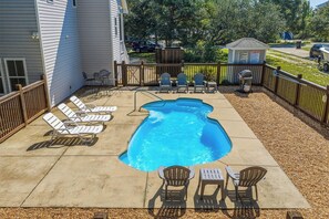 Ein Garten mit Swimmingpool, Liegestühlen und Grillplatz.