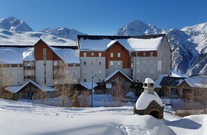 Ein Hotel mit mehreren Gebäuden, schneebedeckten Dächern und einer Bergkulisse.