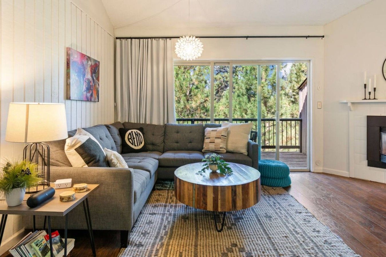 A modern living room with a sectional sofa, a round coffee table, and a view of the outdoors through large windows.