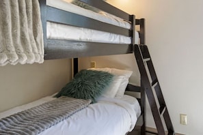 Ein Stockbett mit einer Leiter, einem flauschigen Kopfkissen und einer Decke.