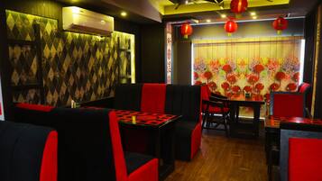 A restaurant interior with red and black seating, a patterned wall, and red lanterns.