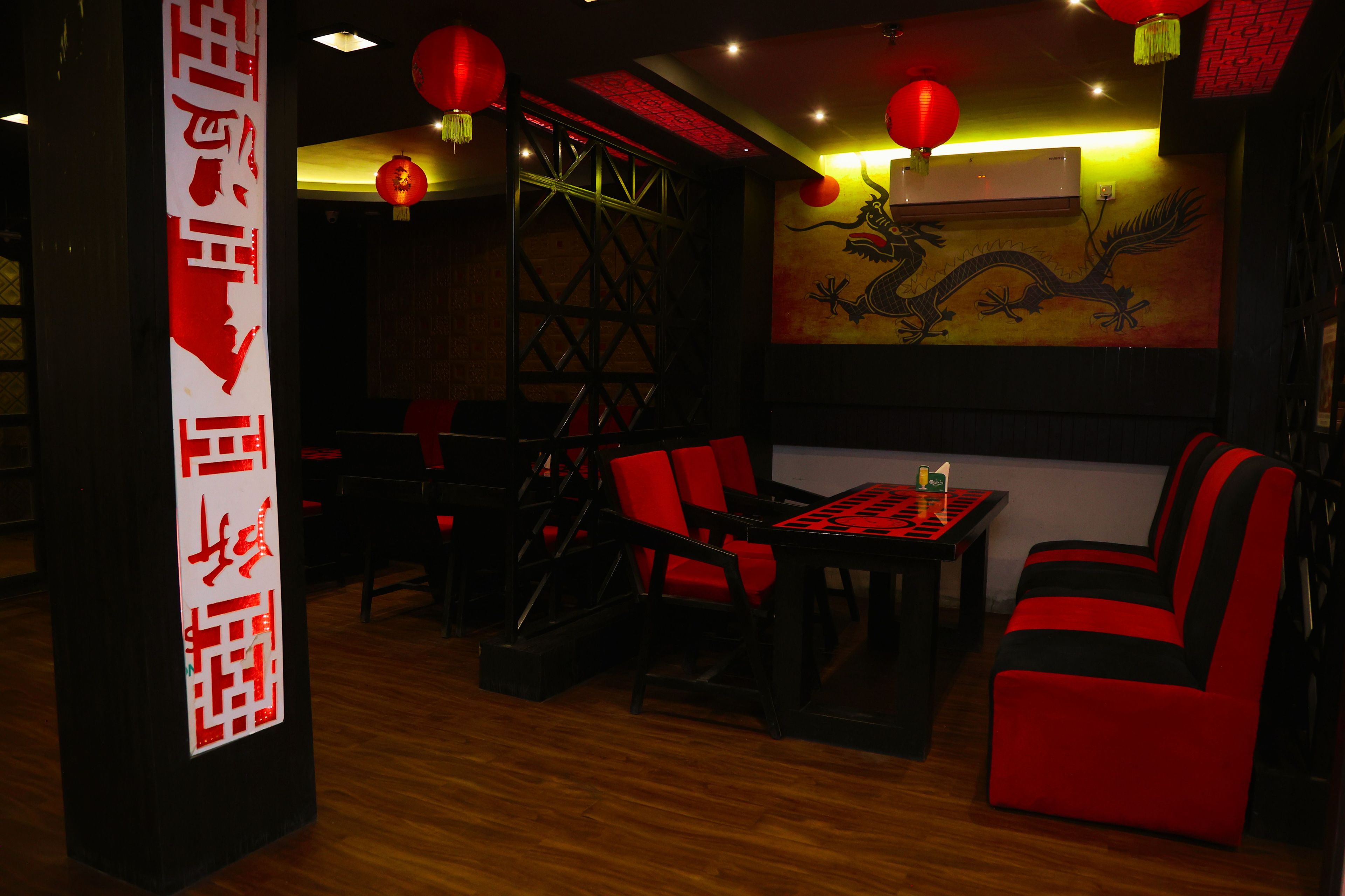 A restaurant interior with red and black furnishings, a dragon mural, and traditional Chinese decor.