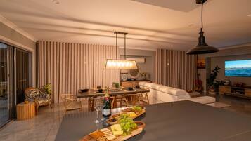 Un salon moderne avec un coin repas, comprenant une grande table dressée pour un repas, un canapé et un téléviseur.