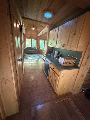 A wooden interior with a kitchen area, a dining area, and a view of the outdoors. - 4-bedroom log cabin in Gladwin on the Tittawassee River with its own boat launch (Gladwin)