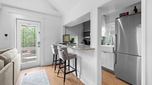 A modern kitchen with a stainless steel refrigerator, a bar area with stools, and a view through a glass door. - StayHaus - The Signature Flat (St. Petersburg)
