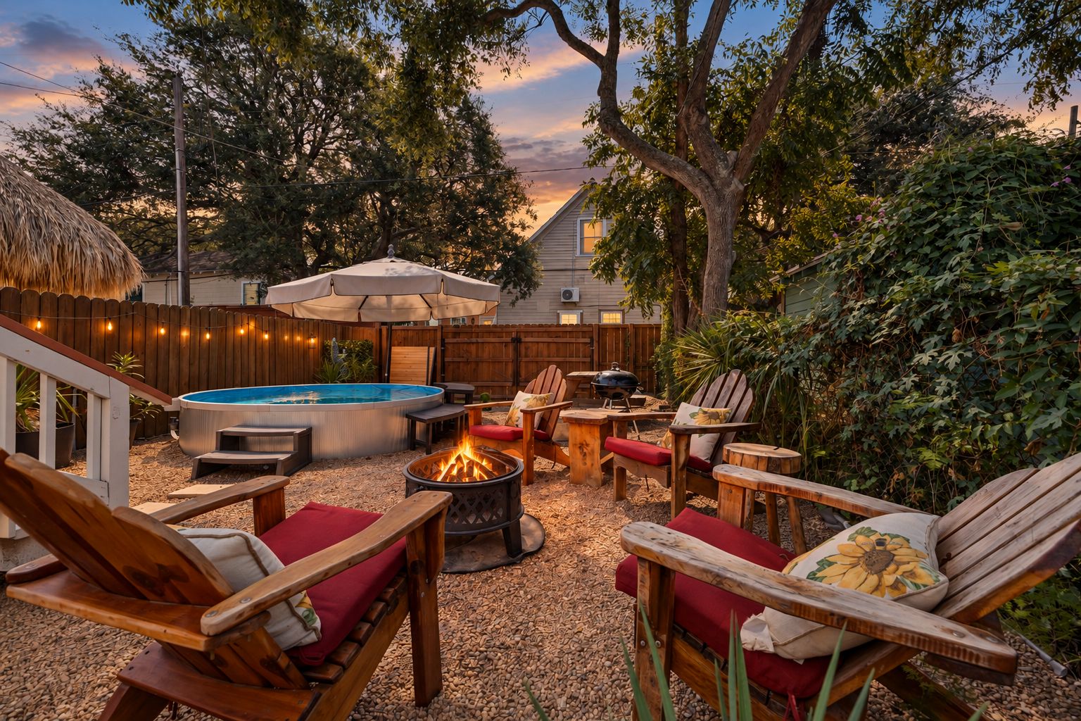 A backyard with a hot tub, fire pit, outdoor furniture, and a wooden fence.