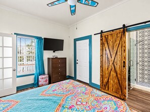 A bedroom with a large bed, a dresser, a TV, and a sliding door. - Pet-Friendly 2BR Galveston Retreat | Cowboy Pool | Sleeps 8 (Galveston)