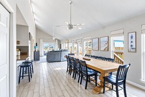 Ein geräumiger Essbereich mit einem langen Holztisch und mehreren Stühlen, der zu einer Küche und einem Balkon mit Aussicht führt.