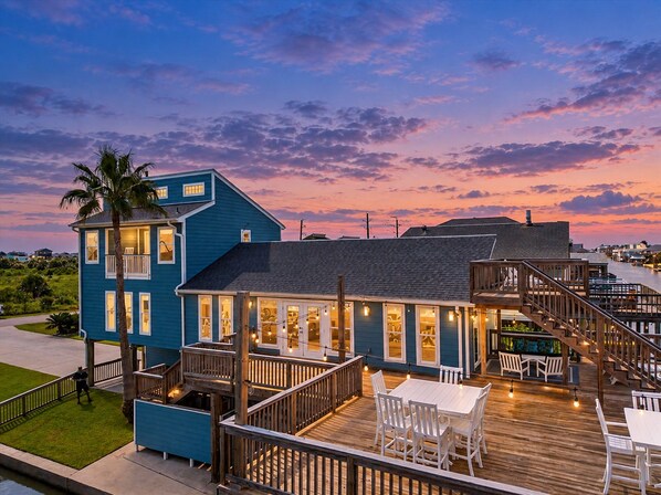 Um imóvel costeiro com um edifício azul, deck externo e vista para a água.