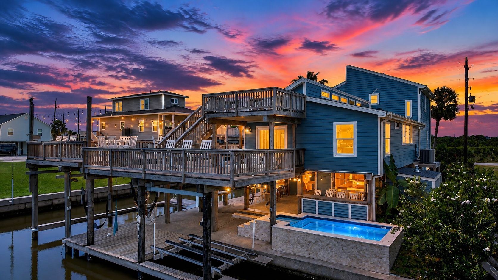 A waterfront property with a multi-level deck, a swimming pool, and a dock extending into the water.