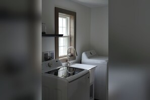 Een wasserette met een wasmachine, een droger en een raam.