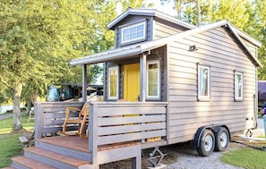 Ein kleines, eingeschossiges Wohnmobil mit Veranda und kleiner Terrasse.