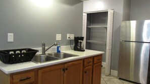 A kitchen with a stainless steel refrigerator, a double sink, wooden cabinets, and a coffee maker. - Downstairs carriage house on Columbus (Savannah)